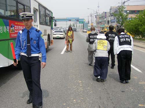 번잡한 길을 지나가는 행렬. 교통정리를 하는 박인영씨의 모습이 보인다. 